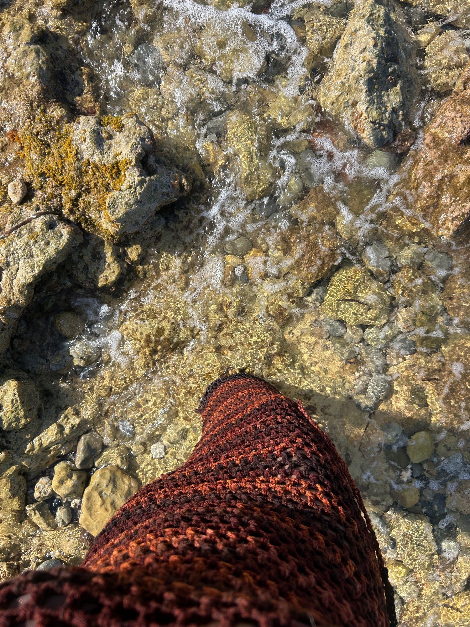 Close-up of handmade crochet mesh fabric showing open-stitch texture and colour variation.